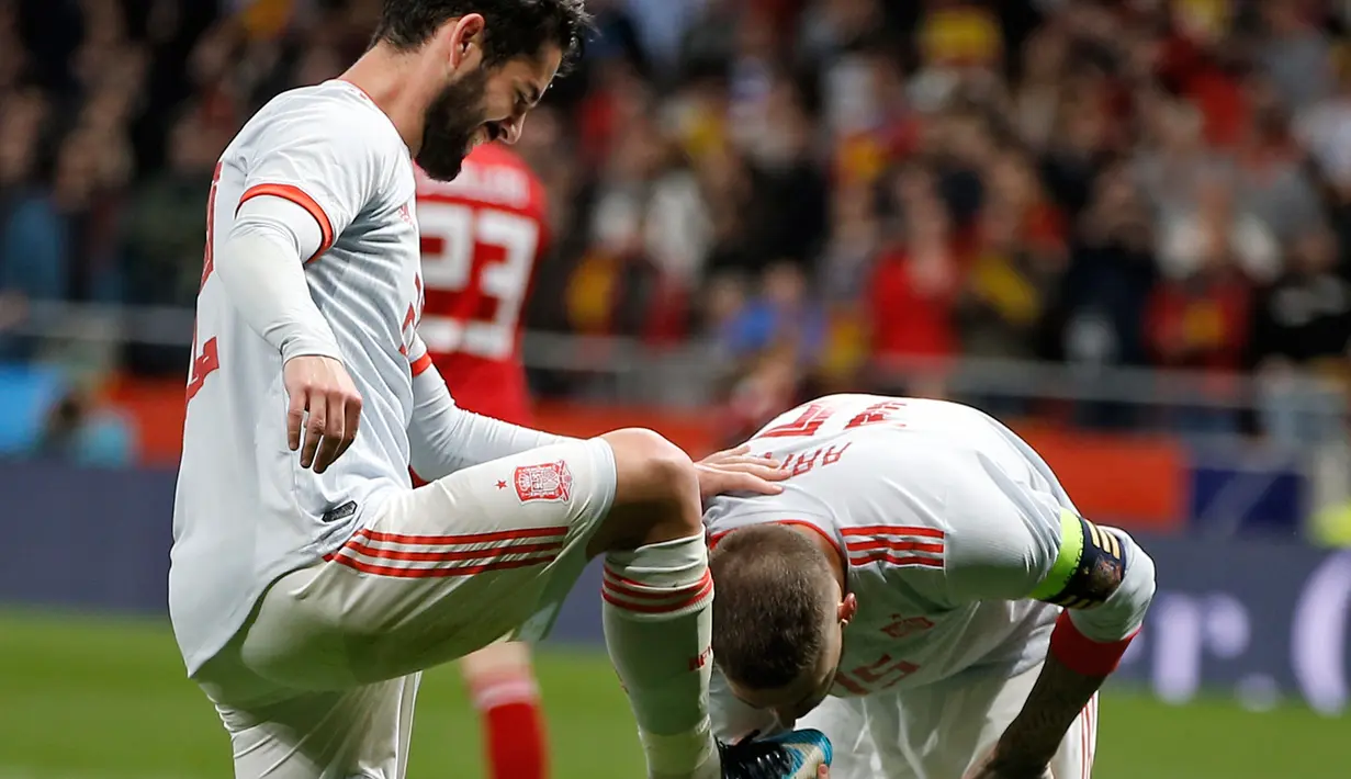 Sergio Ramos mencium sepatu rekan setimnya Isco Alarcon usai mencetak gol kedua saat pertandingan persahabatan melawan Argentina di stadion Wanda Metropolitano di Madrid (27/3). Pada pertandingan itu Spanyol menang 6-1. (AP Photo / Paul White)