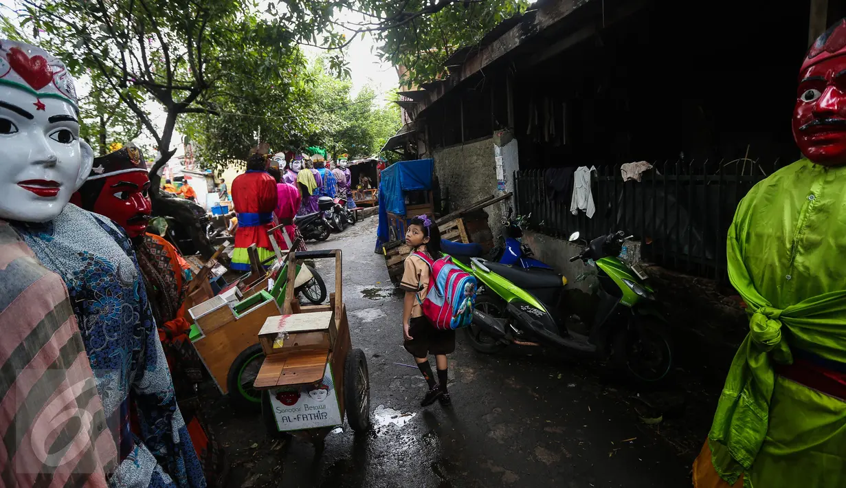 Seorang anak kecil mengamati ondel-ondel yang selesai dibuat di kawasan Kramat, Jakarta, Kamis (26/1). Di awal kemunculannya, ondel-ondel ini berfungsi sebagai penolak bala dari gangguan roh halus yang mengganggu. (Liputan6.com/Faizal Fanani)