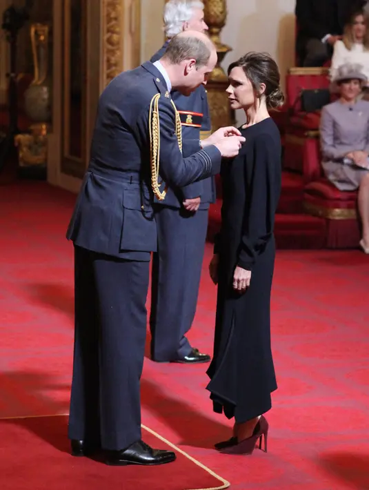 Pangeran William memberikan langsung medali kepada desaomer Victoria Beckham di Istana Buckingham di London, Inggris (19/4). Istri David Beckham ini terlihat tak bisa menyembunyikan perasaan bahagianya. (Yui Mok / PA via AP)