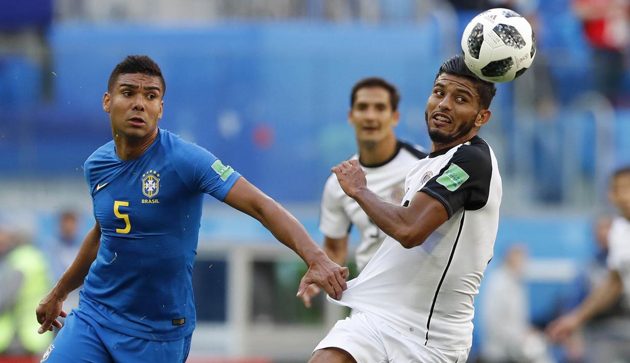 Gelandang Kosta Rika, Johan Venegas, berebut bola dengan gelandang Brasil, Casemiro, pada laga Piala Dunia di Stadion Saint-Petersburg, Jumat (22/6/2018). Brasil menang 2-0 atas Kosta Rika. (AP/Alastair Grant)