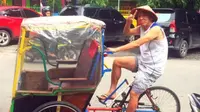 Tony Ho iseng bergaya seperti abang becak di depan rumahnya di Makasar. (Bola.com/Gatot Susetyo)