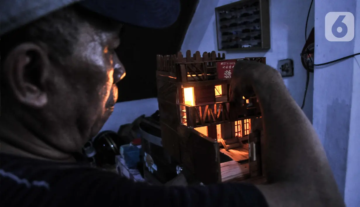Jimmy Alexander (52) memberikan lampu pada miniatur rumah yang dibuatnya saat menyelesaikan pembuatan kerajinan miniatur di kawasan Kalipasir Dalam, Cikini, Jakarta Pusat, Senin (5/9/2022). Untuk pembuatan, Jimmy membutuhkan waktu 4-10 hari dalam menyelesaikan miniatur, tergantung tingkat kesulitan. (merdeka.com/Iqbal S Nugroho)