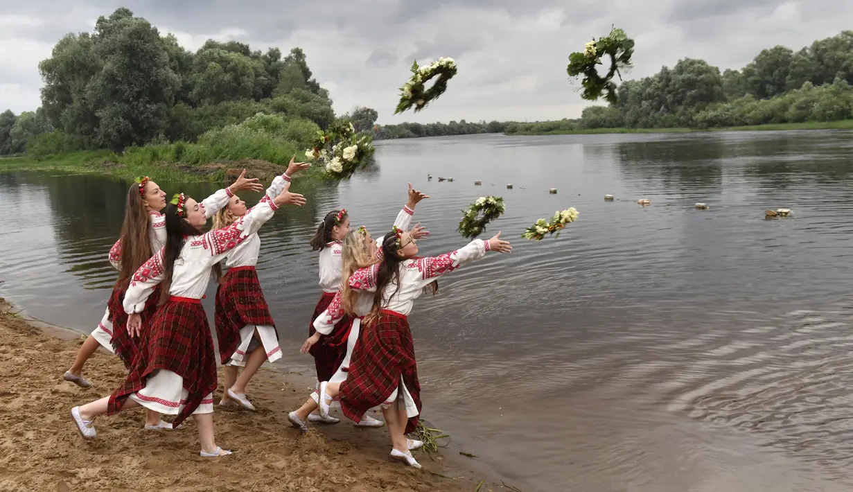 Wanita Belarusia yang mengenakan kostum nasional melemparkan karangan bunga ke Sungai Berezina pada Hari Ivan Kupala di Desa Parichi, sekitar 200 km (125 mil) selatan Parichi, Belarus, 6 Juli 2022. Hari Ivan Kupala merupakan sebuah perayaan malam kuno yang menandai Titik Balik Matahari Musim Panas, malam terpendek tahun ini. (AP Photo/Viktor Drachev)