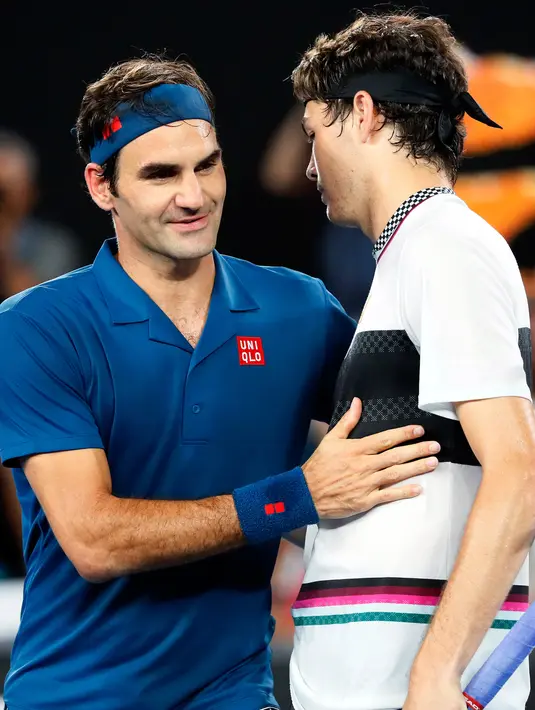 Petenis Swiss, Roger Federer berjabat tangan dengan Taylor Fritz dari AS pada akhir babak 32 besar Australia Terbuka di Melbourne, Jumat (18/1). Federer melaju mulus ke babak 16 besar setelah menang tiga set langsung 6-2 7-5 6-2. (DAVID GRAY/AFP)
