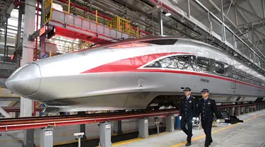 Dua mekanik berjalan melewati sebuah kereta peluru Fuxing CR400AF di stasiun pemeliharaan depo gerbong kereta di Kota Chongqing, China barat (23/12/2020). Kereta yang dioperasikan di Chongqing Railway untuk pertama kalinya, melakukan debut di Chongqing pada Rabu (23/12). (Xinhua/Tang Yi)