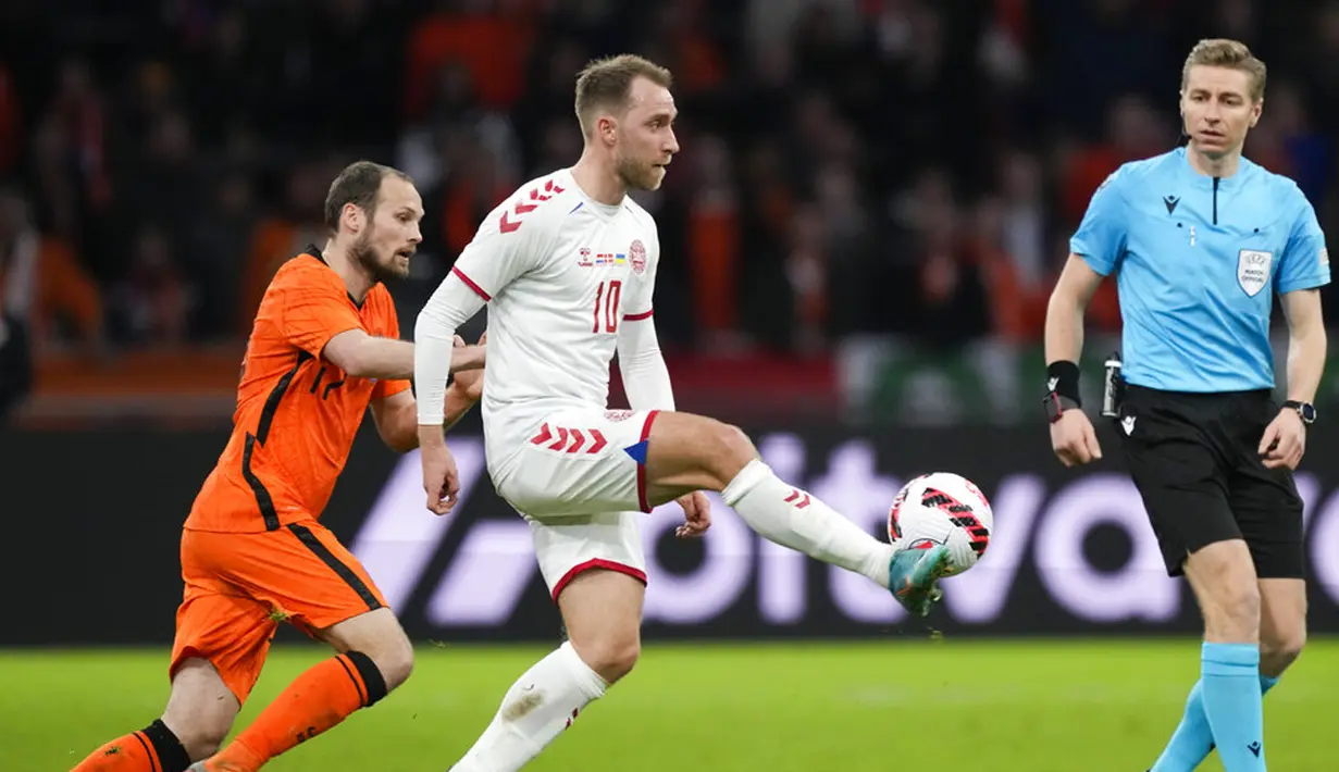 Pemain Denmark Christian Eriksen (tengah) berebut bola dengan pemain Belanda Daley Blind (kiri) disaksikan wasit Lawrence Visser dari Belgia pada pertandingan persahabatan di Johan Cruyff ArenA, Amsterdam, Belanda, 26 Maret 2022. Belanda menang 4-2. (AP Photo/Peter Dejong)