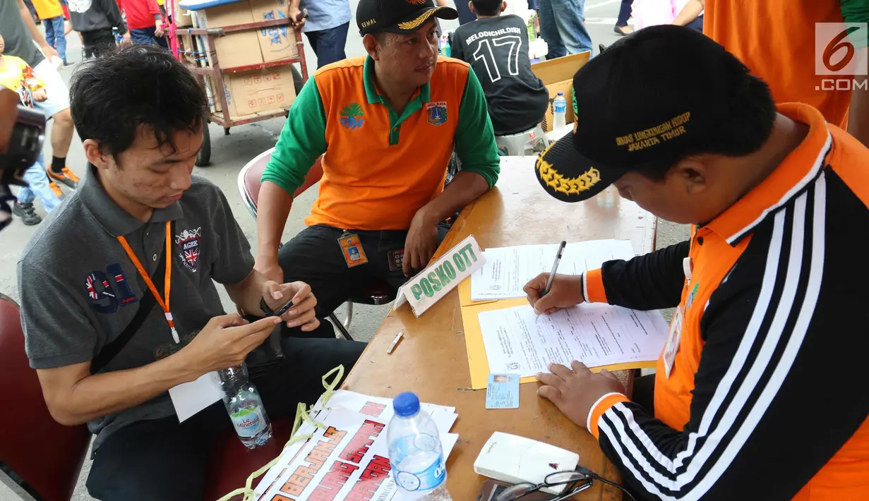 Petugas menindak seorang warga yang tertangkap tangan saat membuang sampah sembarangan di CFD, Jakarta, Minggu (28/1). Petugas juga memberi hukuman sosial atau denda minimal Rp 100.000. (Liputan6.com/Angga Yuniar)