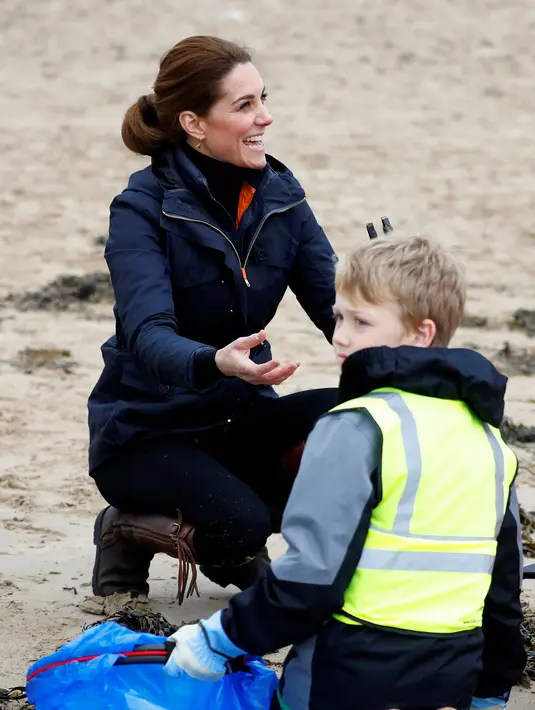 Kate Middleton, Duchess of Cambridge, tersenyum saat membersihkan sampah yang berserakan bersama anak-anak sekolah di pantai Newborough di Wales (8/5). (Reuters/Phil Noble)