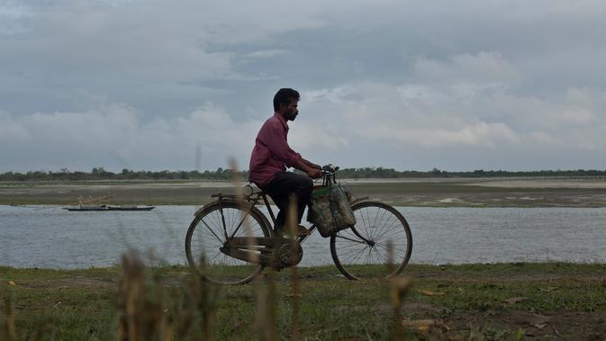 Nelayan mengendarai sepeda di tepi sungai Brahmaputra di Jorhat, Assam, India (3/4). Assam sangat kaya akan sumber daya airnya. Brahmaputra adalah salah satu sungai terbesar di Asia, yang melewati wilayah China Tibet, India dan Bangladesh sebelum konvergen ke Teluk Benggala. (AP Photo/Anupam Nath)