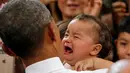 Anak Bayi terlihat menangis menjerit-jerit saat di gendong Presiden AS Barack Obama di Stasiun Udara Korps Marinir Iwakuni, Jepang (27/5). Kedatangan Obama ke Jepang untuk mennghadiri pertemuan G7. (REUTERS/Carlos Barria)
