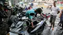 Montir membersihkan sepeda motor konsumen usai terendam banjir di kawasan Mampang, Jakarta, Minggu (21/2/2021). Banjir yang melanda Ibu Kota Jakarta pada Sabtu (20/2) menyebabkan banyak kendaraan warga mengalami kerusakan akibat terendam air. (Liputan6.com/Faizal Fanani)