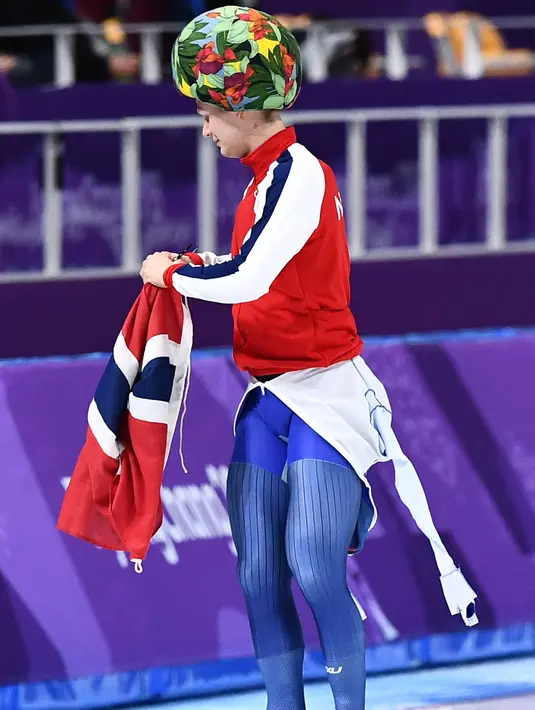 Atlet Norwegia Haavard Lorentzen memakai topi bermotif kembang saat merayakan kemenangan meraih medali emas di acara skating 500m putra selama Olimpiade Musim Dingin Pyeongchang 2018 di Gangneung Oval di Gangneung (19/2). (AFP Photo/Aris Messinis)
