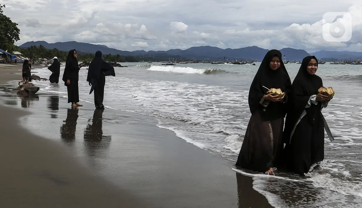 Warga berjalan di Pantai Pelabuhan Ratu, Kabupaten Sukabumi, Jawa Barat, Jumat (12/11/2021). Pantai Pelabuhan Ratu menjadi tempat wisata favorit warga Jawa Barat serta Jakarta dan sekitarnya. (Liputan6.com/Johan Tallo)