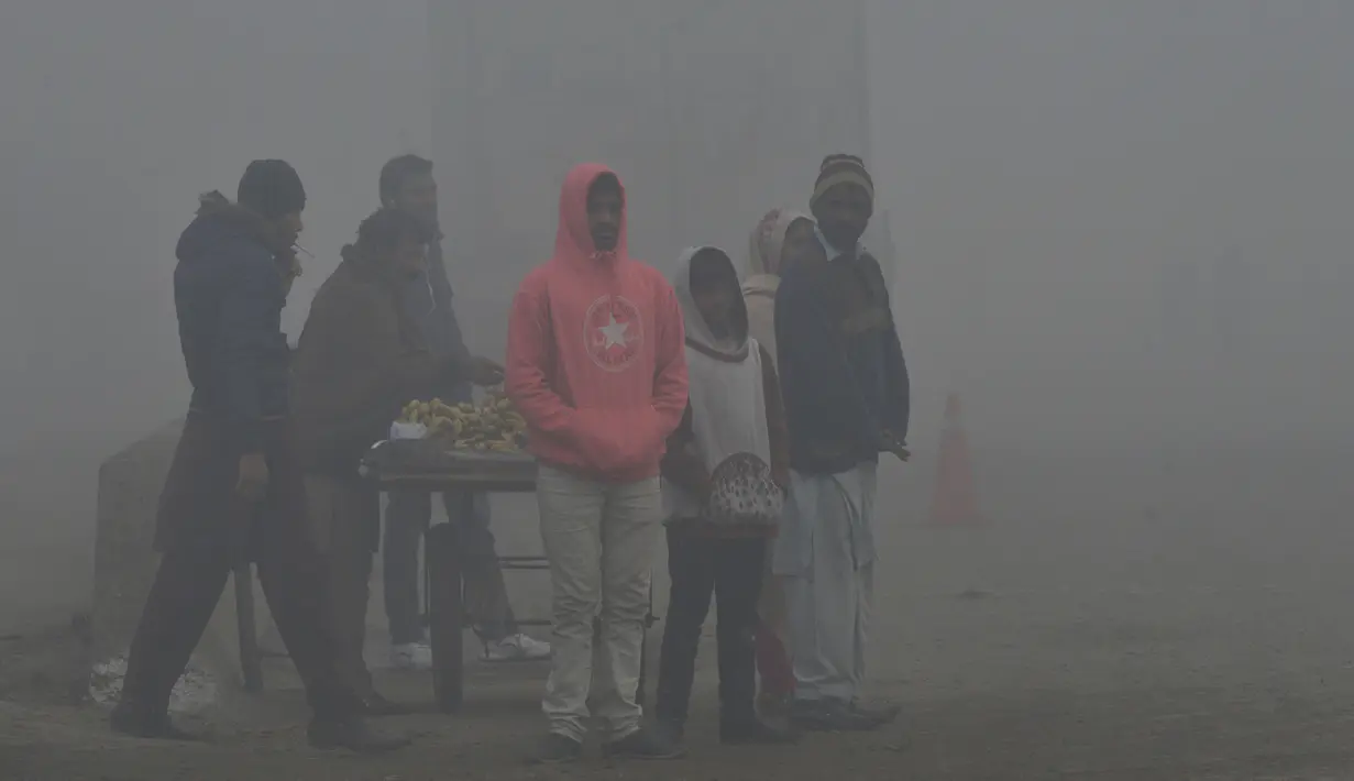 Penduduk Pakistan menunggu angkutan di tengah kabut asap tebal di Lahore (3/1). Tingkat kabut asap melonjak selama musim dingin di Pakistan selatan, ketika kualitas udara melampaui level aman Organisasi Kesehatan Dunia. (AFP Photo/Arif Ali)