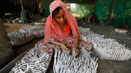 Pekerja mengisi tabung dengan gulungan kertas berisi bubuk mesiu untuk petasan, di sebuah pabrik pinggiran Ahmadabad, Senin (22/10). Permintaan petasan di India semakin meningkat jelang perayaan Festival "Cahaya" Diwali bagi umat Hindu. (AP/Ajit Solanki)