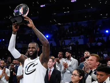 Pemain tim LeBron James, LeBron James mengangkat tropi usai timnya mengalahkan tim Stephen dalam pertandingan basket NBA All Star di Los Angeles, Amerika Serikat, Minggu (18/2). Tim LeBron menang dengan skor 148-145. (AP Photo/Chris Pizzello)