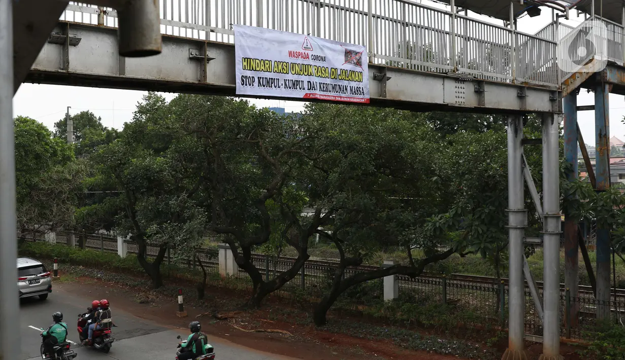 Pengendara melintasi bawah Jembatan Penyeberangan Orang (JPO) di Jalan Raya Lenteng Agung, Jakarta, Selasa (17/3/2020). Sebuah spanduk berisi ajakan menghindari kerumunan dan kumpul-kumpul untuk mencegah penyebaran virus Corona COVID-19 terpasang di JPO teresebut. (Liputan6.com/Helmi Fithriansyah)