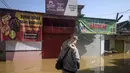 Badan Penanggulangan Bencana Daerah (BPBD) Kabupaten Bandung mencatat tiga kecamatan terendam banjir akibat luapan Sungai Citarum. Tampak dalam foto, seorang pria mengevakuasi kucingnya sambil mengarungi jalan yang terendam banjir di Bandung, Jawa Barat, pada Jumat 5 Desember 2025. (TIMUR MATAHARI/AFP)