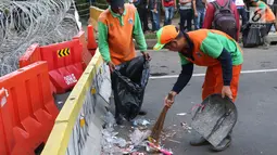 Petugas PPSU membersihkan sampah sisa perayaan Hari Buruh Internasional di kawasan Silang Barat Daya Monas, Jakarta, Rabu (1/5). Buruh dari sejumlah perkumpulan merayakan Hari Buruh Internasional dengan aksi damai. (Liputan6.com/Helmi Fithriansyah)