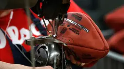 Pekerja menjahit bola american football di pabrik di Wilson Sporting Goods di  Ada, Ohio, AS (23/1). Dalam proses penjahitan, pekerja menggunakan mesin jahit lama untuk membuat sekitar 3.000 bola per hari. (AP Photo/Charles Rex Arbogast)