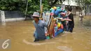 Warga membantu mendorong gerobak penjual prabotan di komplek Polri jalan Pondok Karya, Mampang, Jakarta, Kamis (21/4). Banjir setinggi 120cm disebabkan meluapnya Kali Mampang. (Liputan6.com/Gempur M Surya)