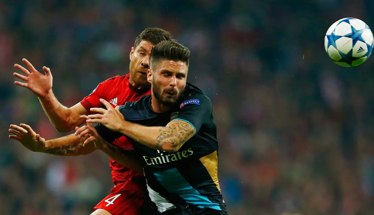 Penyerang Arsenal, Oliver Giroud berebut bola udara dengan gelandang Bayern Muenchen, Xabi Alonso pada lanjutan Grup F liga champions di stadion Allianz Arena, Munich, Jerman (4/11). Muenchen menang atas Arsenal dengan skor 5-1. (Reuters/Michael Dalder) 