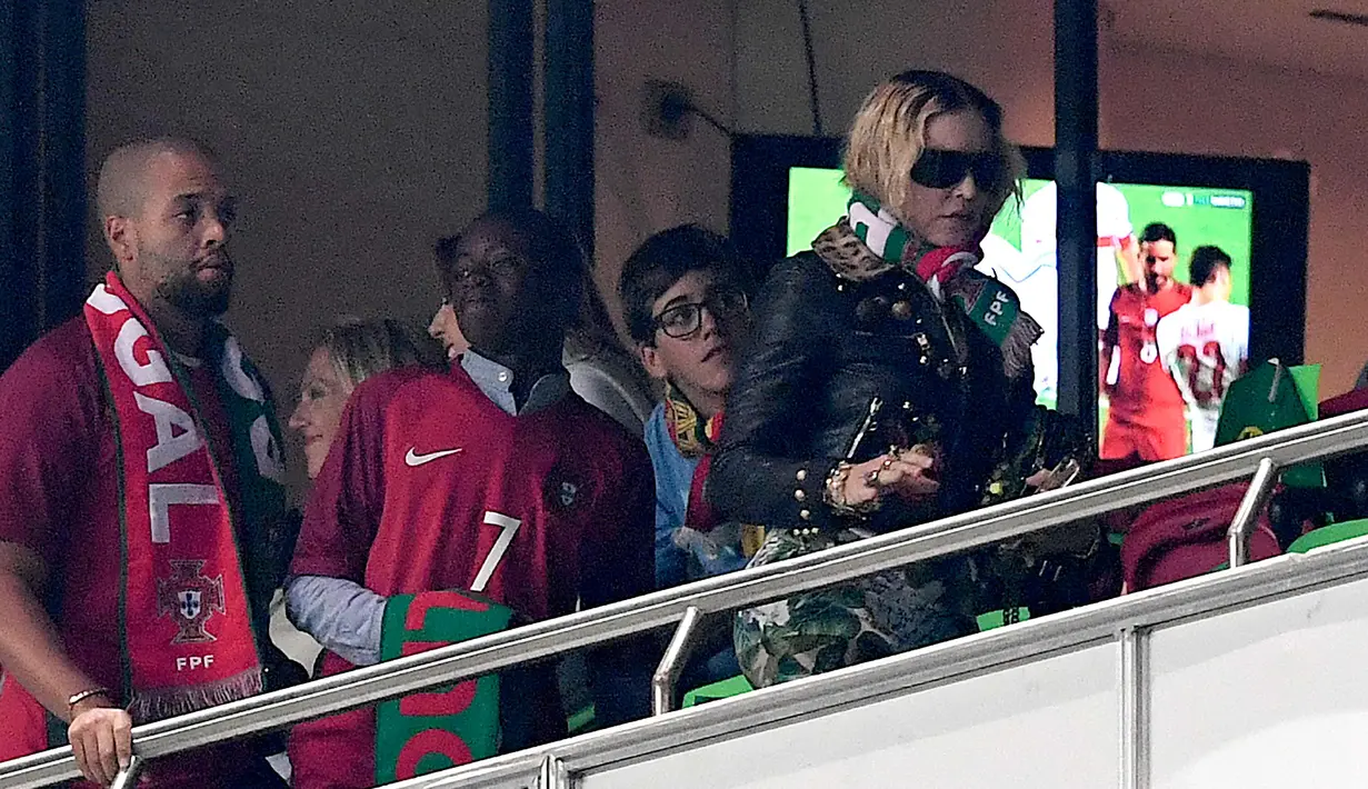 Penyanyi AS, Madonna berbincang dengan anaknya David Banda menyaksikan pertandingan kualifikasi Piala Dunia 2018 antara Portugal dan Swiss di Stadion Luz di Lisbon (10/10). Portugal menang 2-0 atas Swiss. (AFP Photo/Francisco Leong)