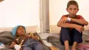 Foto yang diambil dari Video, Dua orang anak laki-laki beristirahat saat menerima perawatan akibat keracunan makanan di Sebuah tenda medis di kamp Hassan Sham U2, Irak (13/6). (AP Photo / Balint Szlanko)