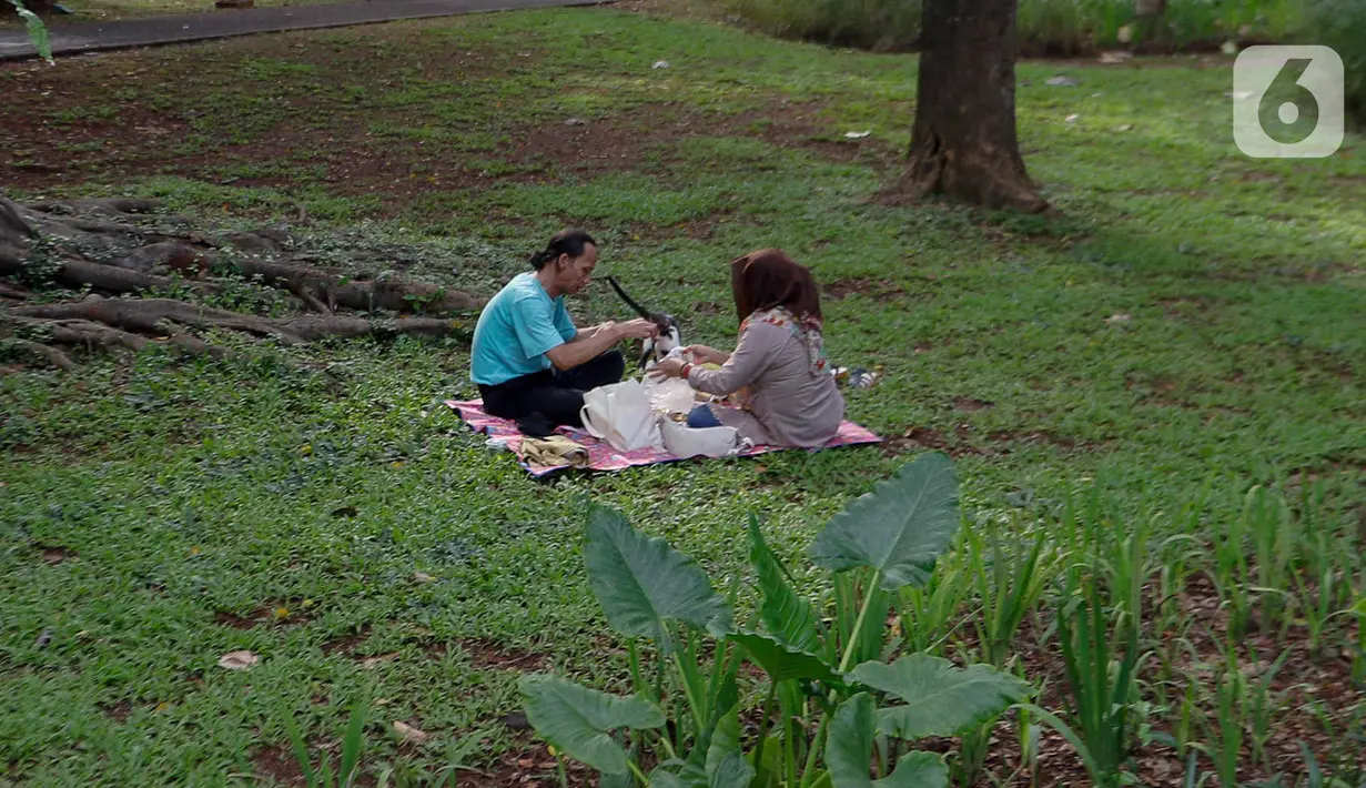 Warga membawa bekal makanan sambil menggelar tikar saat berwisata di Tebet Eco Park, Tebet, Jakarta, Senin (15/4/2024). (Liputan6.com/Herman Zakharia)