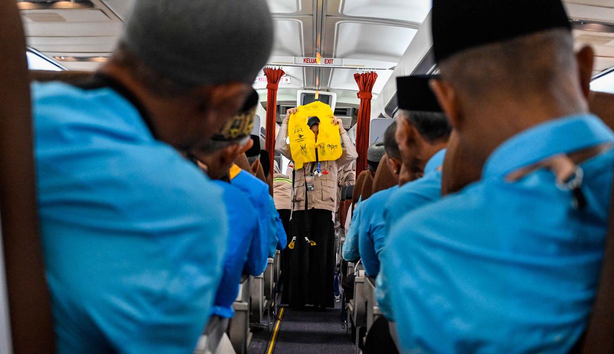 Para calon jemaah haji Indonesia menyimak cara menggunakan jaket penyelamat dari awak kabin di dalam pesawat Boeing 717 yang sudah tidak digunakan lagi selama sesi pelatihan keselamatan pra-keberangkatan di pusat embarkasi haji Banda Aceh pada Kamis 14 Mei 2026. (CHAIDEER MAHYUDDIN/AFP)