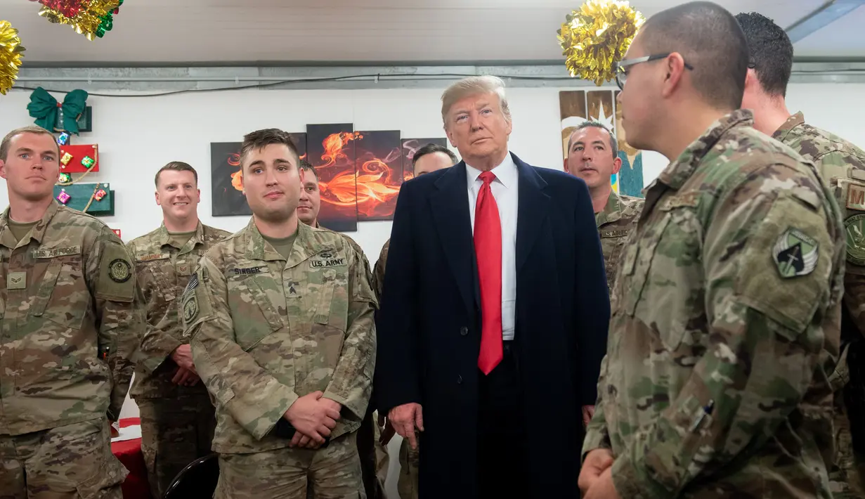 Presiden Donald Trump menyapa pasukan militer Amerika dalam kunjungan kejutan ke Pangkalan Udara al Asad, Irak, Rabu (26/12). Kunjungan ini merupakan kunjungan perdananya setelah mengumumkan penarikan pasukan militer dari Suriah. (SAUL LOEB/AFP)