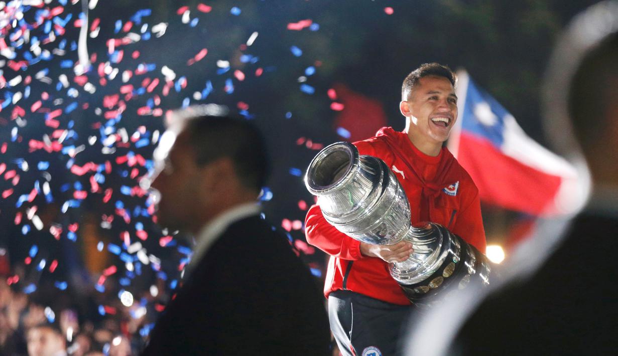 Alexis Sanchez dengan trofi Copa America menyambut suporter Cile dari balkon Istana Presiden. (REUTERS/Mariana Bazo)