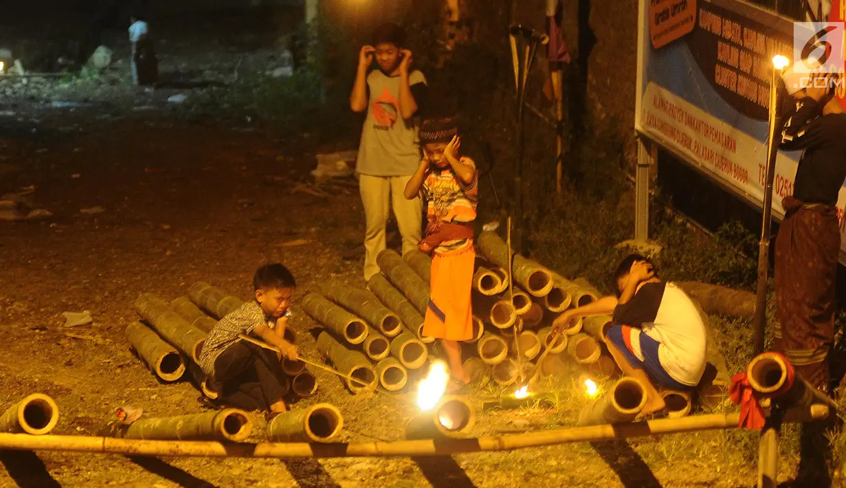Anak-anak bermain meriam bambu atau bledugan saat merayakan malam takbiran di kawasan Cijeruk, Bogor, Jawa Barat, Selasa (4/6/2019). Bledugan memanfaatkan karbit yang dimasukkan ke dalam meriam bambu untuk kemudian diledakkan. (merdeka.com/Arie Basuki)