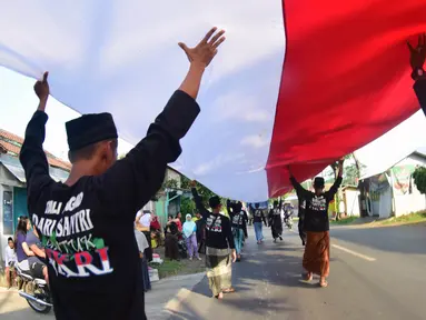 Sejumlah santri dari Pondok Pesantren Ashabul Kahfi membawa bendera Merah Putih besar saat mengikuti pawai Hari Santri Nasional 2017 di Gunungpati, Semarang (22/10). (Liputan6.com/Gholib)