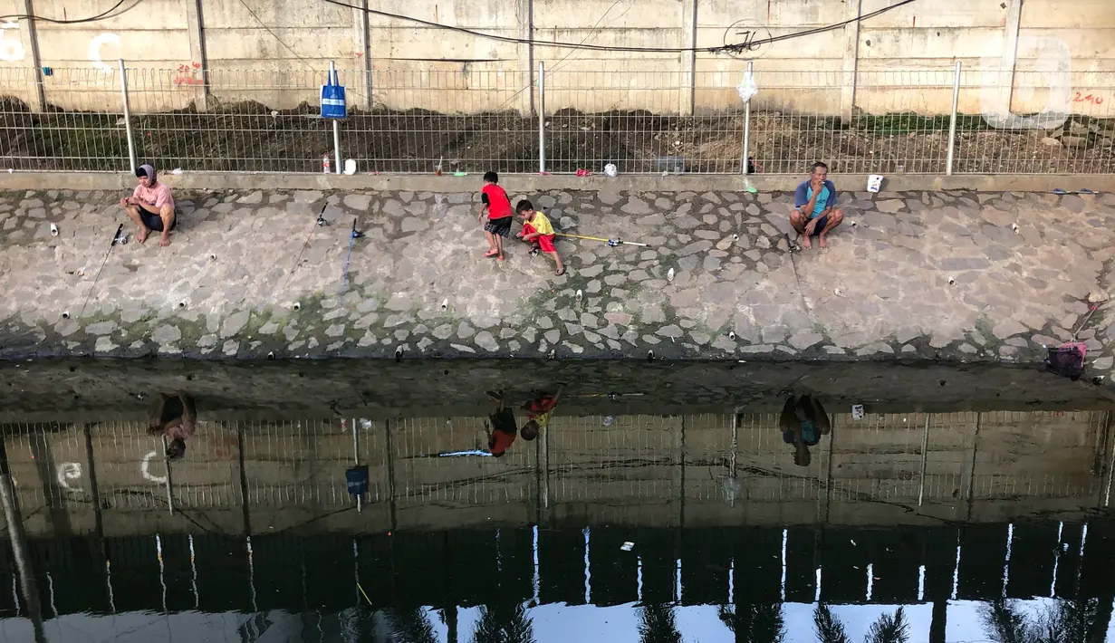 Sejumlah warga memancing ikan di kubangan yang berada di Jalan DI Panjaitan, Jatinegara, Jakarta, Selasa (16/6/2020). Meski telah dipagari, sejumlah warga tetap memancing ikan di lokasi yang merupakan saluran pembuangan tersebut. (Liputan6.com/Immanuel Antonius)