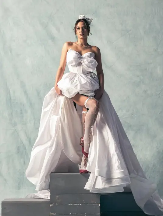 Dalam potret tersebut, Valerie tampil mengenakan gaun putih pengantin yang seksi. Dengan model strapless bergaya heart neck. Semakin menarik dengan model gaun korset di bagian atas berpita besar. [@valerieethomas]