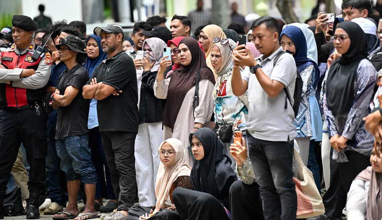 Warga menyaksikan sebelas pria dan wanita menjalani hukuman cambuk setelah dinyatakan bersalah melanggar hukum syariat Islam Aceh yang melarang hubungan seksual di luar nikah di Banda Aceh, Kamis, 20 Agustus 2026. (AFP/ Chaideer Mahyuddin)