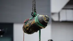 Alat berat mengangkat bom era Perang Dunia II yang ditemukan di lokasi konstruksi di distrik padat Wan Chai, Hong Kong, Kamis (1/2). Para ahli bekerja semalaman untuk menjinakkan bom seberat 450 kg tersebut. (AFP/ Anthony WALLACE)