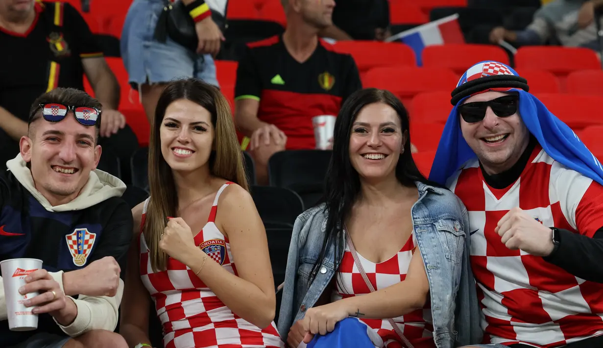 Dua fans wanita Kroasia bersama rekannya menghadiri pertandingan Grup F Piala Dunia Qatar 2022 antara Kroasia dan Belgia di Stadion Ahmad Bin Ali di Al-Rayyan, barat Doha pada 1 Desember 2022. (AFP/Gabriel Bouys)