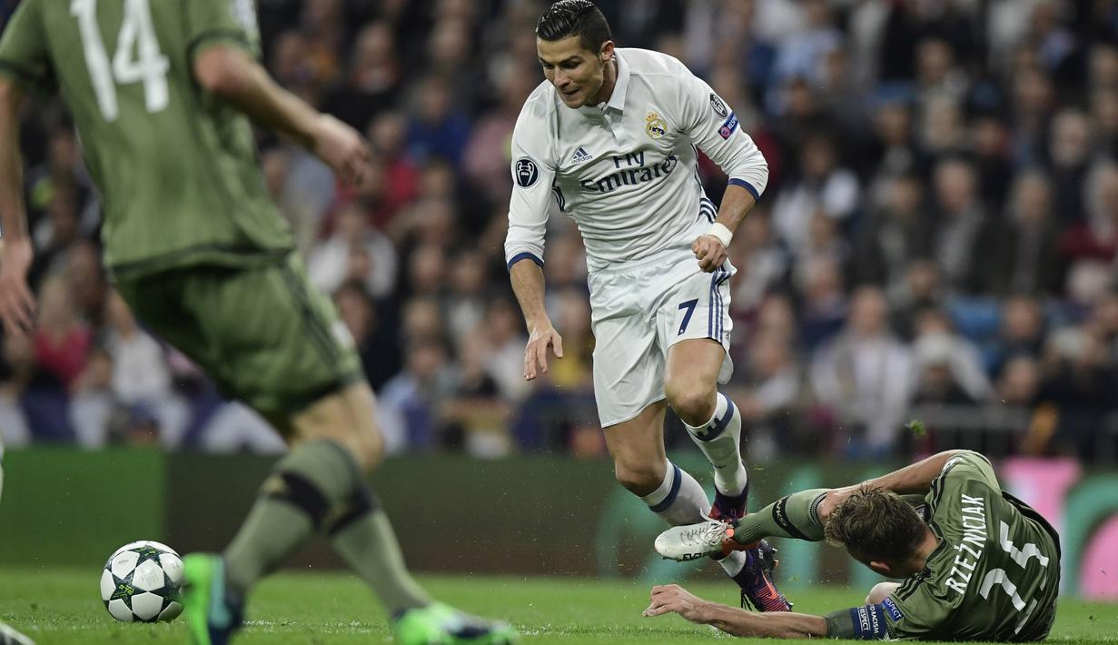 Cristiano Ronaldo berusaha melewati hadangan pemain Legia Warszawa, Jakub Rzezniczak pada laga grup F Liga Champions di Santiago Bernabeu stadium, Madrid, Rabu (19/10/2016) dini hari WIB. (AFP/Javier Sorano)  