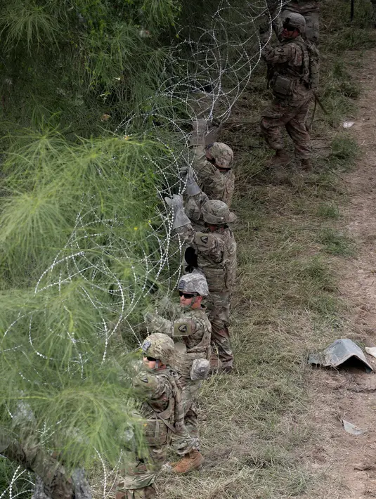 Tentara AS memasang kawat duri sepanjang perbatasan AS dengan Meksiko dekat Jembatan Internasional McAllen-Hidalgo,Texas, Jumat (2/11). Departemen Pertahanan AS memfokuskan pasukan ke kawasan Texas, Arizona, dan California. (AP Photo/Eric Gay)