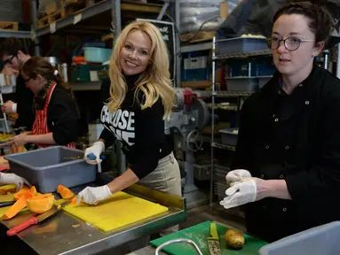 Aktris AS, Pamela Anderson membantu menyiapkan makanan untuk imigran di sebuah kamp di Calais, Prancis, 3 Mei 2017. Model panas era 90-an itu membantu kegiatan relawan di kamp tersebut, seperti memasak dan memilah selimut. (FRANCOIS LO PRESTI/AFP)