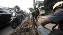 Pengendara melintas dekat pekerja yang tengah menyelesaikan proyek revitalisasi trotoar di Jalan Tebet Raya, Jakarta, Selasa (5/11/2019). Adanya proyek revitalisasi trotoar tersebut mengakibatkan kemacetan di kawasan itu semakin parah, terlebih saat jam sibuk. (merdeka.com/Iqbal Nugroho)