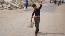 Saat ini, di antara infrastruktur yang runtuh dan sumber daya yang menipis, warga Gaza bergantung pada bantuan air terbatas, yang distribusinya sering terhambat oleh situasi keamanan. Tampak dalam foto, seorang pemuda Palestina membawa wadah air di Kota Gaza, Selasa 12 Mei 2026. (AP Photo/Abdel Kareem Hana)