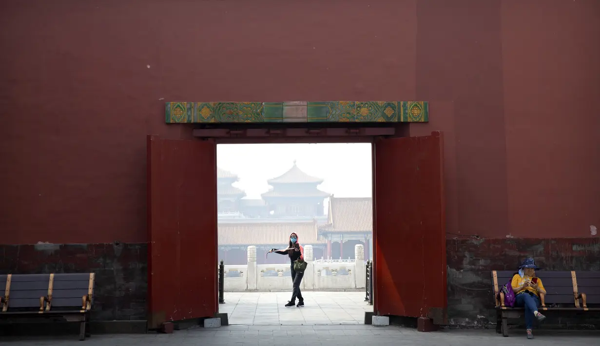 Pengunjung mengenakan masker saat berjalan di Kota Terlarang, Beijing, China, Jumat (1/5/2020). Kota Terlarang kembali dibuka setelah ditutup lebih dari tiga bulan karena pandemi virus corona COVID-19. (AP Photo/Mark Schiefelbein)