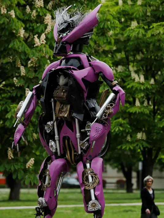 Warga berjalan melihat sejumlah robot mirip karakter film Transformers yang dipamerkan di pusat kota Zagreb, Kroasia (18/4). Robot ini dibuat dengan memanfaatkan bangkai mobil rusak akibat kecelakaan. (REUTERS/Antonio Bronic)