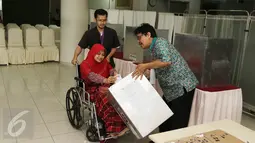 Pasein RSCM Hikna Solehah dibantu petugas memasukan surat suara saat mengikuti Pilkada DKI 2017 di TPS 15 RSCM, Jakarta, Rabu (15/2/2017). (Liputan6.com/Herman Zakharia)