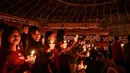 Umat Kristiani menyalakan lilin selama misa Hari Natal di Gereja Bethany, Surabaya, Jawa Timur pada Kamis 25 Desember 2025. (JUNI KRISWANTO/AFP)