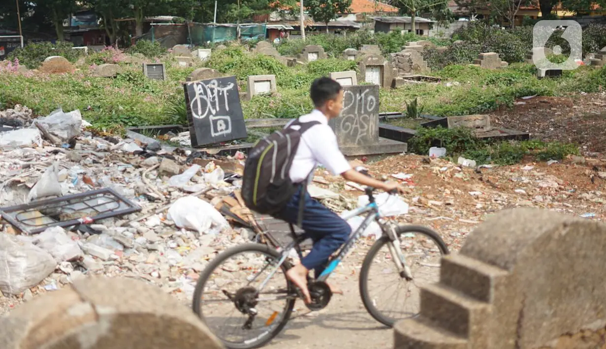 Seorang siswa melintas di sekitar Taman Pemakaman Umum (TPU) Menteng Pulo, Jakarta, Selasa (3/12/2019). Pemprov DKI Jakarta berencana merevitalisasi 17 TPU serta akan melakukan perluasan lahan makam hingga 794,83 hektar. (Liputan6.com/Immanuel Antonius)