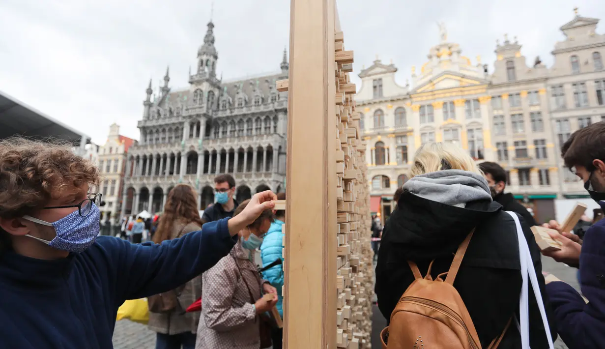 Orang-orang mengambil sejumlah balok kayu dari "The Disappearing Wall" di Grand Place, Brussel, Belgia, 3 Oktober 2020. Instalasi seni memperingati 30 tahun reunifikasi Jerman itu terdiri dari 6.000 balok kayu dilengkapi kutipan para seniman dan pemikir dari seluruh dunia. (Xinhua/Zheng Huansong)